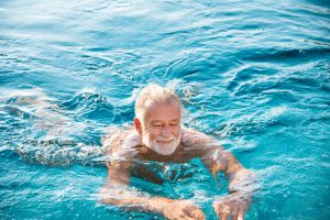 Ein älterer Herr schwimmt in einem Pool.