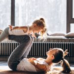 Eine junge Mutter macht mit ihrer kleinen Tochter Yoga.