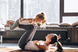 Eine junge Mutter macht mit ihrer kleinen Tochter Yoga.