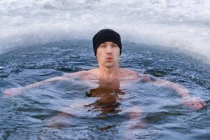 Ein junger Mann mit Mütze beim Eisbaden.