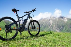 Ein E-Bike steht auf einer Wiese inmitten einer Berglandschaft.
